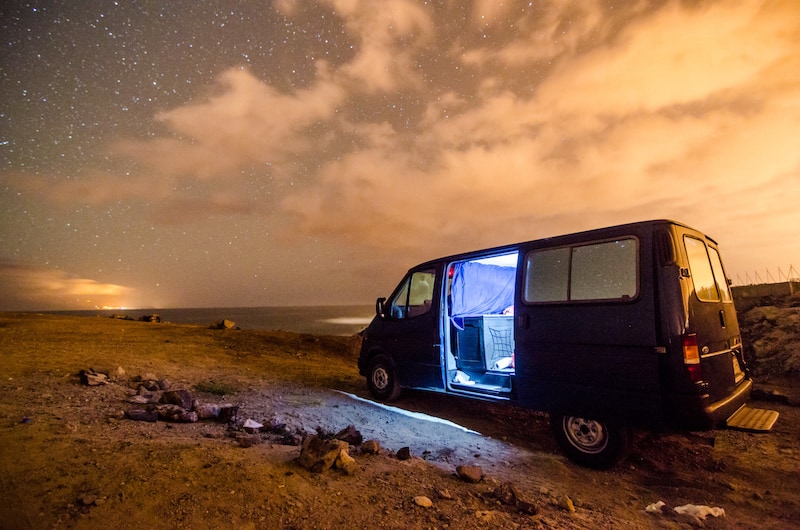 a camper van under a starry night with the door open 