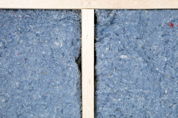 a close up of recycled cotton batt insulation in a wood framed wall